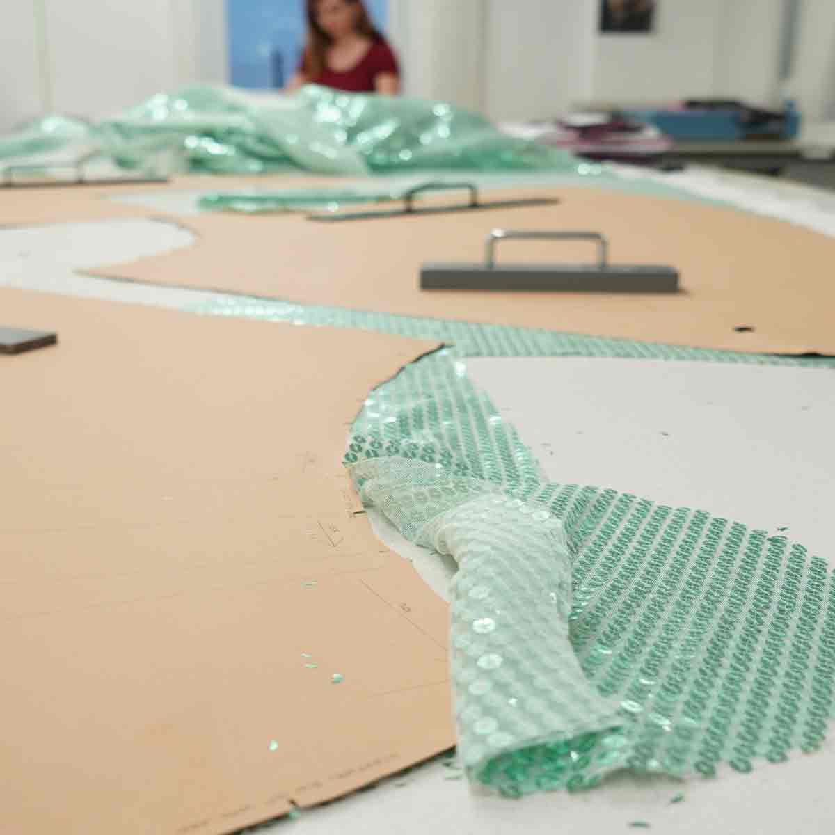 Two people reviewing pink and black garment samples in the studio